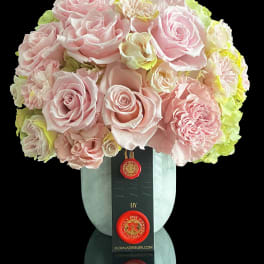 Pink rose bouquet in a pale blue vase with a black ribbon tag