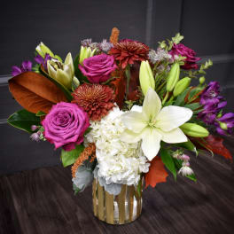 Mixed bouquet of roses, lilies, hydrangea, and chrysanthemums in a gold vase