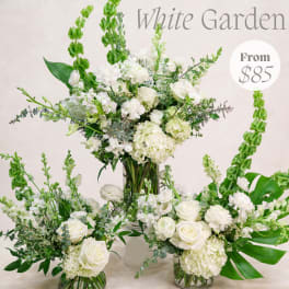 White floral arrangement in a glass vase with tall green spikes