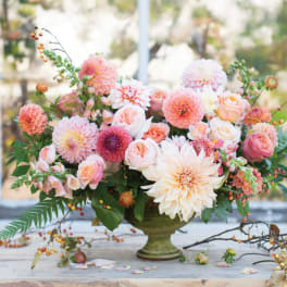Peach and pink floral arrangement in a green pedestal vase