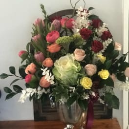 Mixed bouquet of roses, tulips, and orchids in a silver vase