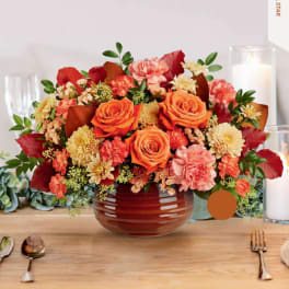 Orange roses and peach carnations in a red vase