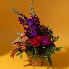 Mixed bouquet in a woven basket with red and purple flowers