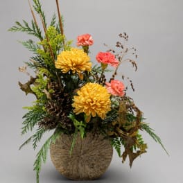 Yellow chrysanthemums and pink carnations in a rustic vase arrangement