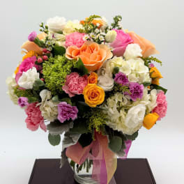Mixed bouquet of roses, carnations, and hydrangeas in a glass vase
