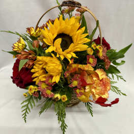 Basket arrangement with sunflowers, red roses, and mixed fall flowers