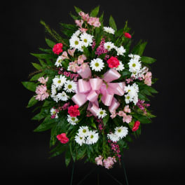 Standing floral spray with white daisies, pink flowers, and a pink ribbon bow
