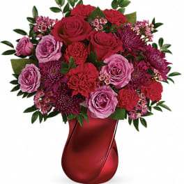 Red and pink rose bouquet in a red vase