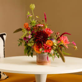 Colorful mixed flower arrangement in a low glass vase on a white table