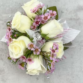 White rose bouquet with pink accent flowers and a jeweled ribbon