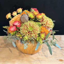 Mixed orange and pink flowers arranged in a pumpkin-shaped container