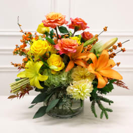 Bright mixed bouquet in a clear glass vase with roses and lilies