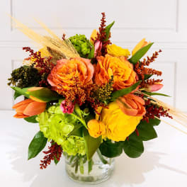 Orange and yellow floral arrangement in a clear glass vase