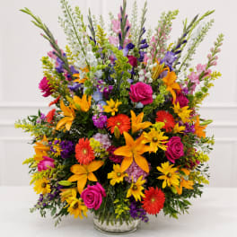 Colorful mixed bouquet in a clear glass vase with roses, lilies, and daisies
