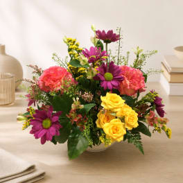 Colorful flower arrangement in a white bowl vase on a table