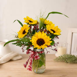 Sunflower bouquet in a mason jar with a red plaid ribbon