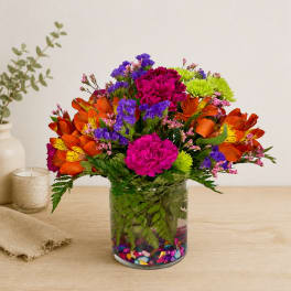 Colorful mixed bouquet in a clear glass vase with decorative stones