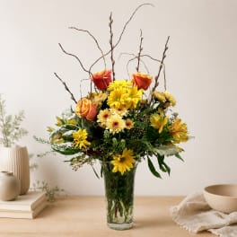 Mixed yellow and orange flowers in a clear glass vase
