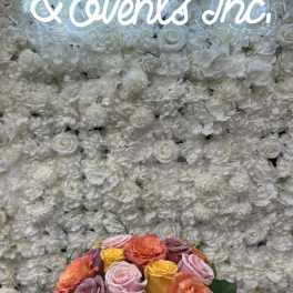 Mixed roses in a glass vase before a white floral wall