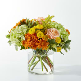 Mixed orange and yellow flowers in a clear glass vase