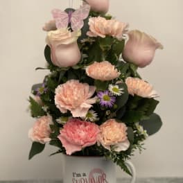 Pink and peach floral arrangement in a mug with a survivor message