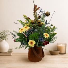 Mixed floral arrangement in a brown handled container with a fish accent