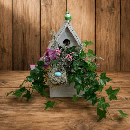 Birdhouse planter with ivy, pink accents, and a nest decoration
