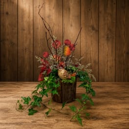 Autumn floral arrangement in a rustic wood container with a bird ornament
