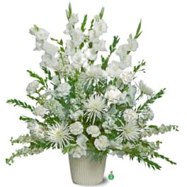 Tall all-white sympathy arrangement with gladiolus, carnations, and mums in a cream ceramic pot
