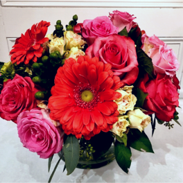 Bouquet of pink and red roses with a red gerbera daisy in a vase