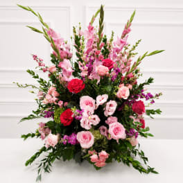 Large pink and red floral arrangement with roses and tall spikes