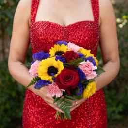 Woman holding a bouquet of red roses, sunflowers, pink carnations, and purple filler flowers