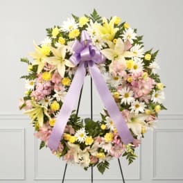 Pastel floral wreath with lilies, daisies, and a lavender ribbon bow