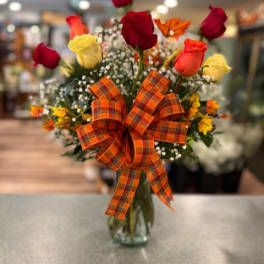 Bouquet of red and yellow roses in a glass vase with an orange plaid bow