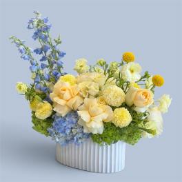 Blue and cream floral arrangement in a white ribbed vase