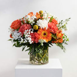 Mixed orange and white bouquet in a clear glass vase