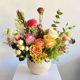 Mixed bouquet of roses, dahlias, and white blooms in a white vase