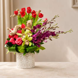 Mixed bouquet of red, pink, and purple flowers in a patterned white vase