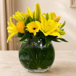 Yellow lilies and a gerbera daisy in a clear glass vase