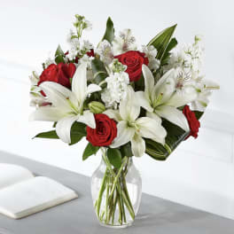 Red roses and white lilies arranged in a clear glass vase