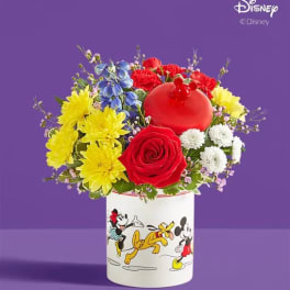 Colorful bouquet in a Mickey Mouse vase with red, yellow, blue, and white flowers.
