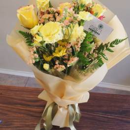 Bouquet of yellow roses and mixed blooms wrapped in cream paper