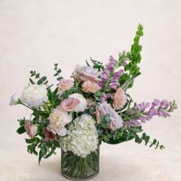 Pastel bouquet in a clear glass vase with white, pink, and purple blooms