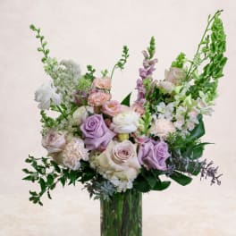 Pastel bouquet of roses, carnations, and snapdragons in a glass vase