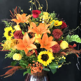 Mixed bouquet with orange lilies, sunflowers, and roses in a vase