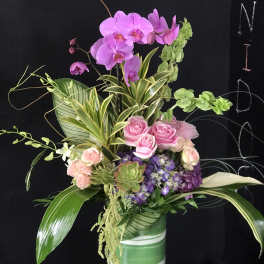 Pink orchids and roses in a green striped vase