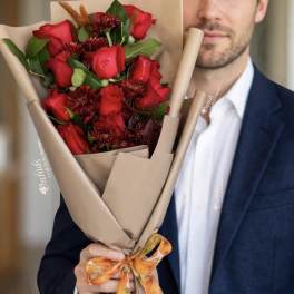 Man holding a bouquet of red roses wrapped in tan paper
