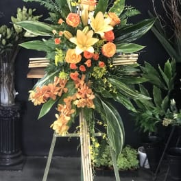 Tall orange and yellow floral standing spray on an easel
