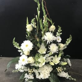 White floral arrangement with daisies, lilies, and roses in a low display