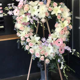 Heart-shaped floral wreath on an easel with pink and white flowers